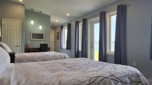 A bedroom with two beds, a ceiling fan, a TV, and a window with curtains. - Seawind Landing Country Inn (Charlos Cove)