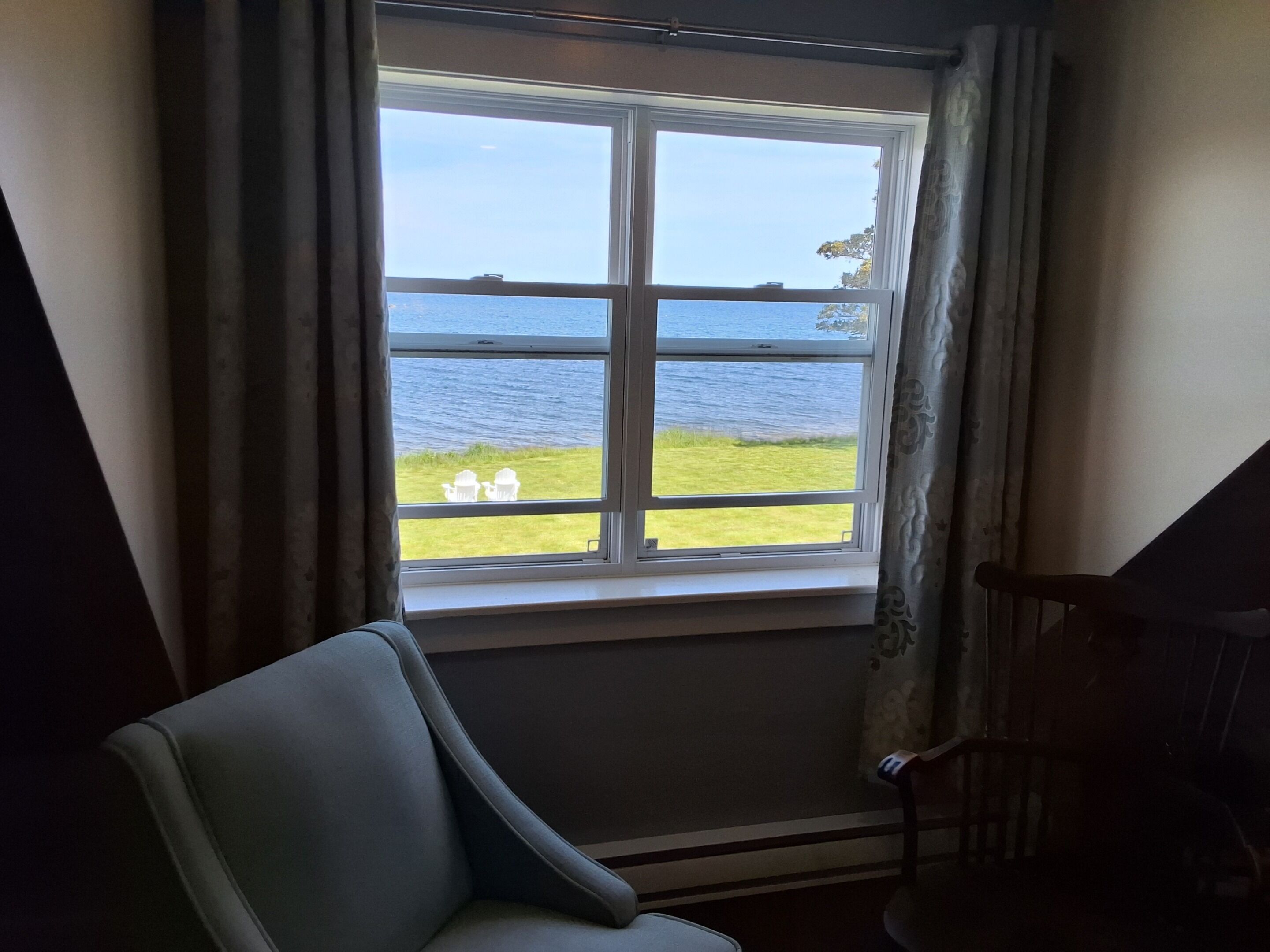 A room with a large window overlooking a body of water and grassy area.