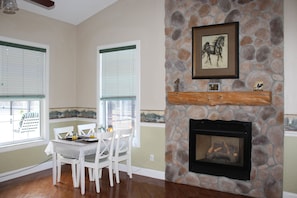 A dining area with a stone fireplace, white chairs, and a table set for two. - Rock Pointe Ranch (Floral City)