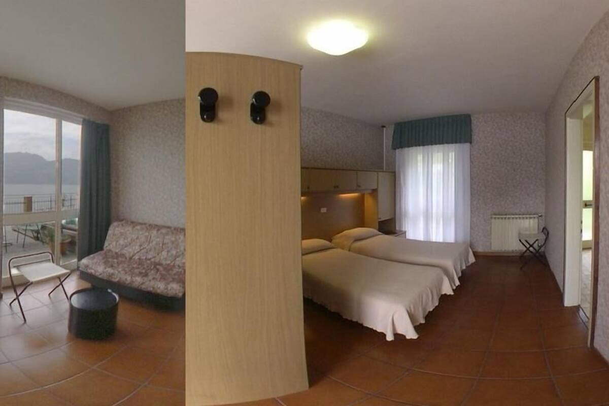 Een hotelkamer met balkon, een bank, twee bedden en een houten zuil.