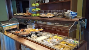 Un buffet proposant une variété de plats, notamment des fruits, des pâtisseries et des options pour le petit-déjeuner.
