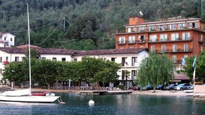 Un bâtiment situé sur la côte, doté d’une façade rouge, de murs blancs et de nombreux balcons donnant sur l’eau.