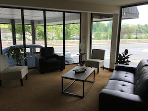 Relax in our inviting lobby, featuring a comfortable seating area with a sofa and armchairs, a coffee table, and floor-to-ceiling windows offering views of the surrounding area.