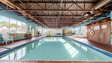 An indoor swimming pool with clear blue tiles, a wooden ceiling, and a view of the outside.. River Rapids Inn