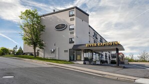 A modern hotel with a sign reading 'River Rapids Inn' and a large windowed entrance. - River Rapids Inn (Niagara Falls)