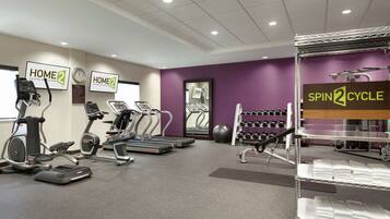 A gym with treadmills, elliptical machines, and a spin cycle area.