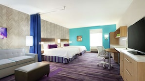 A hotel room with a sofa, two beds, a desk, a TV, and a bathroom. - Home2 Suites by Hilton West Monroe (West Monroe)