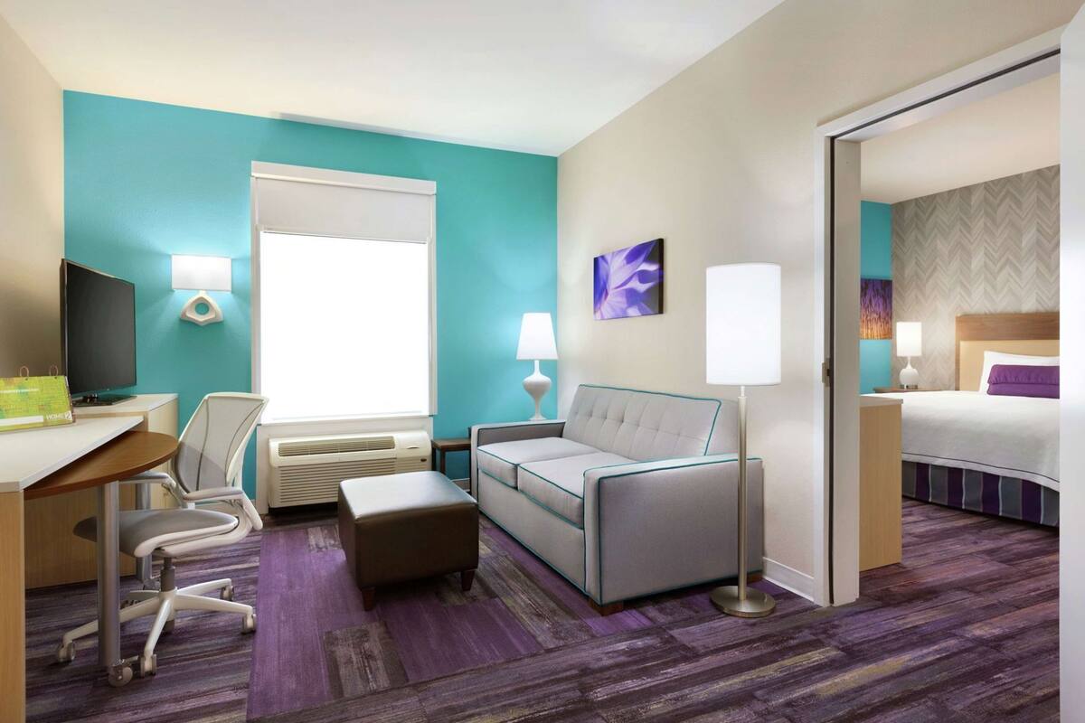 A hotel room with a desk, chair, sofa, and bed.
