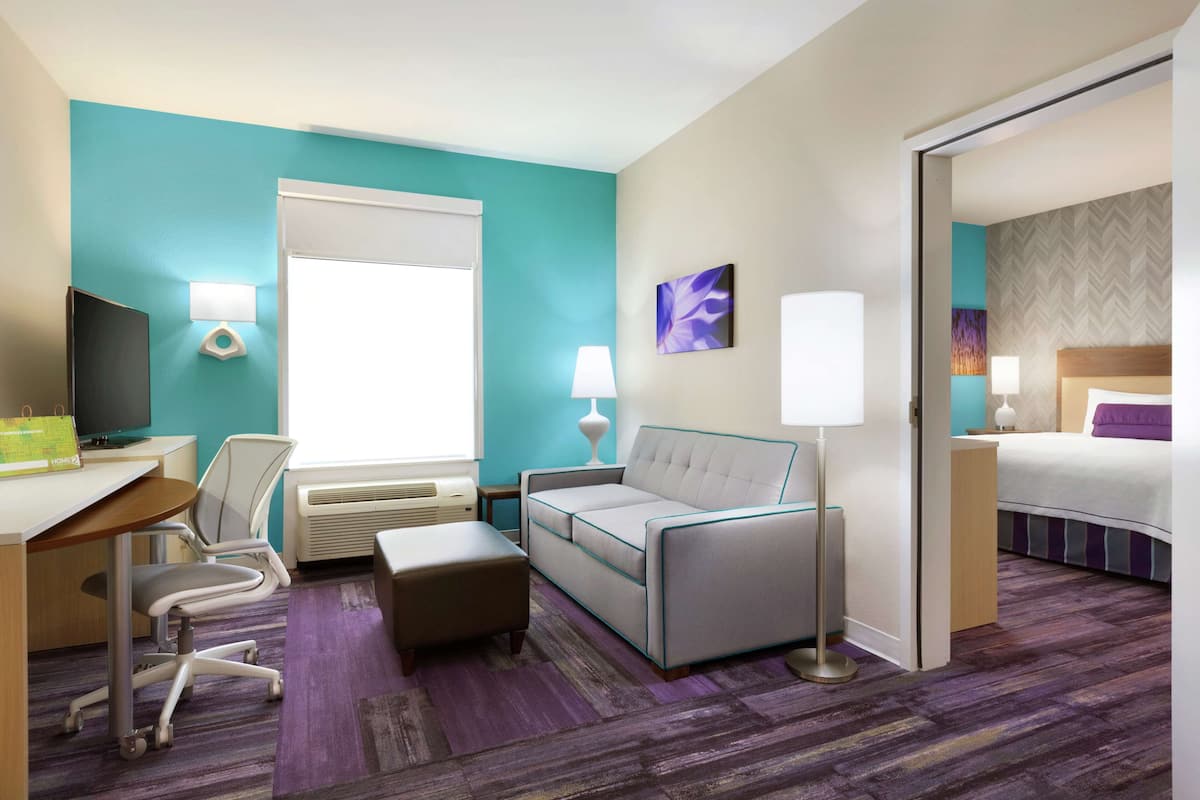 A hotel room with a desk, chair, sofa, and bed.