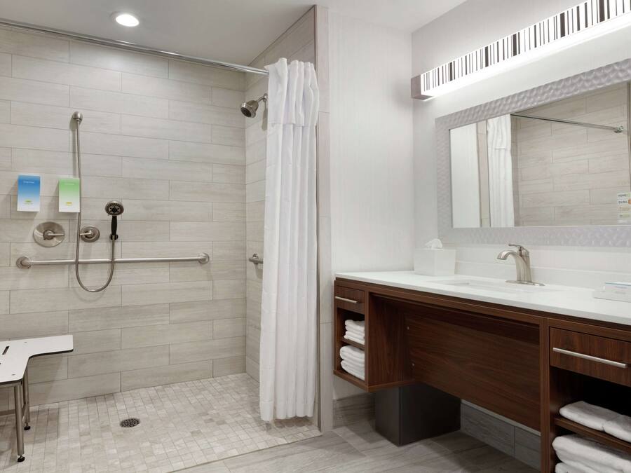 A modern bathroom with a shower, a vanity with a mirror, and a toilet.