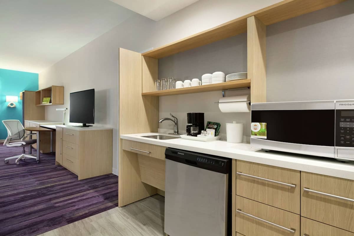 A compact kitchen with a dishwasher, microwave, and a coffee maker on the counter.