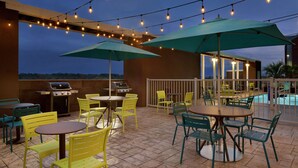 An outdoor patio area with string lights, green umbrellas, and outdoor furniture. - Home2 Suites by Hilton West Monroe (West Monroe)