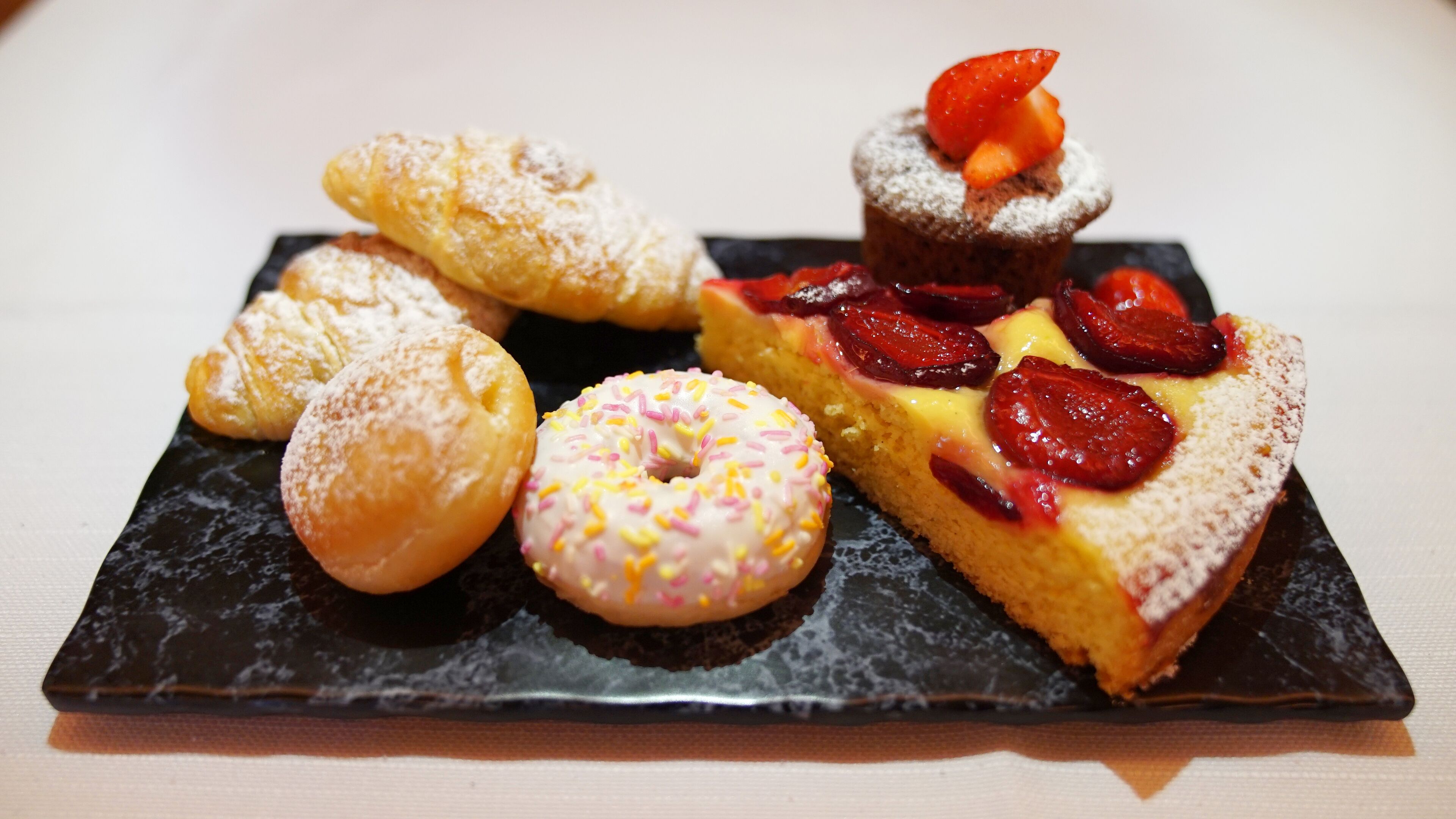 A variety of pastries on a black slate plate.