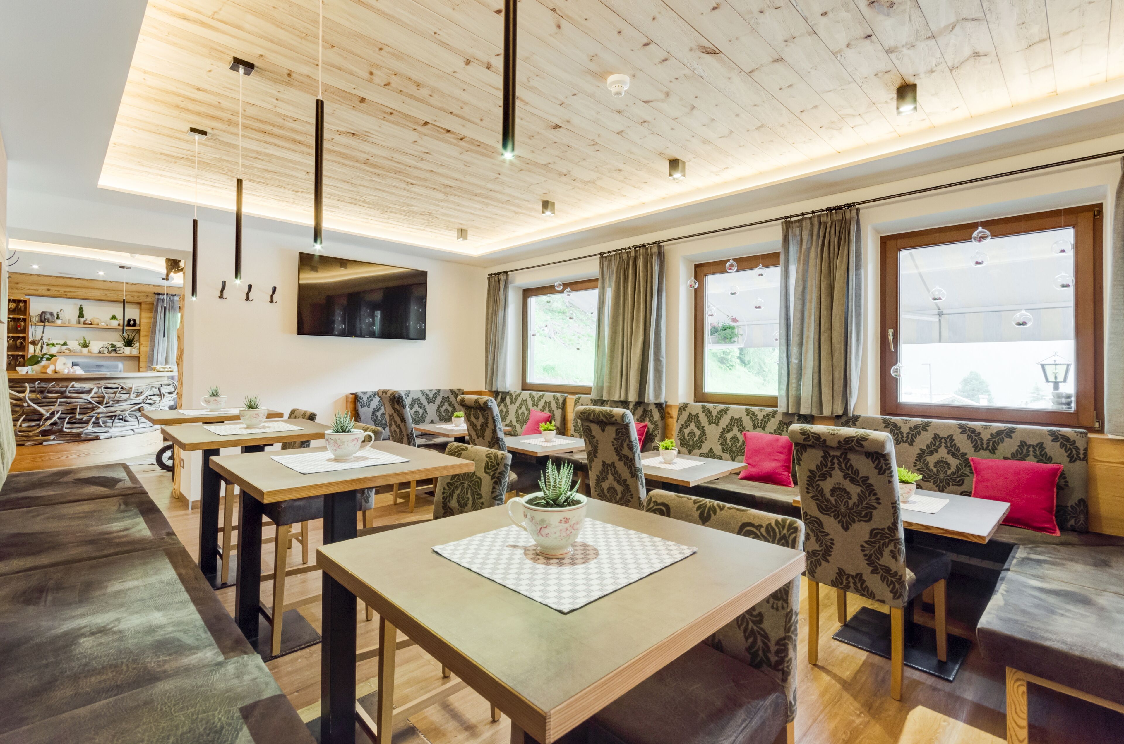 Un comedor moderno con mesas de madera, asientos acolchados y ventanas amplias.