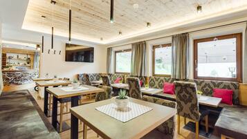 Un comedor moderno con mesas de madera, asientos acolchados y ventanas amplias.