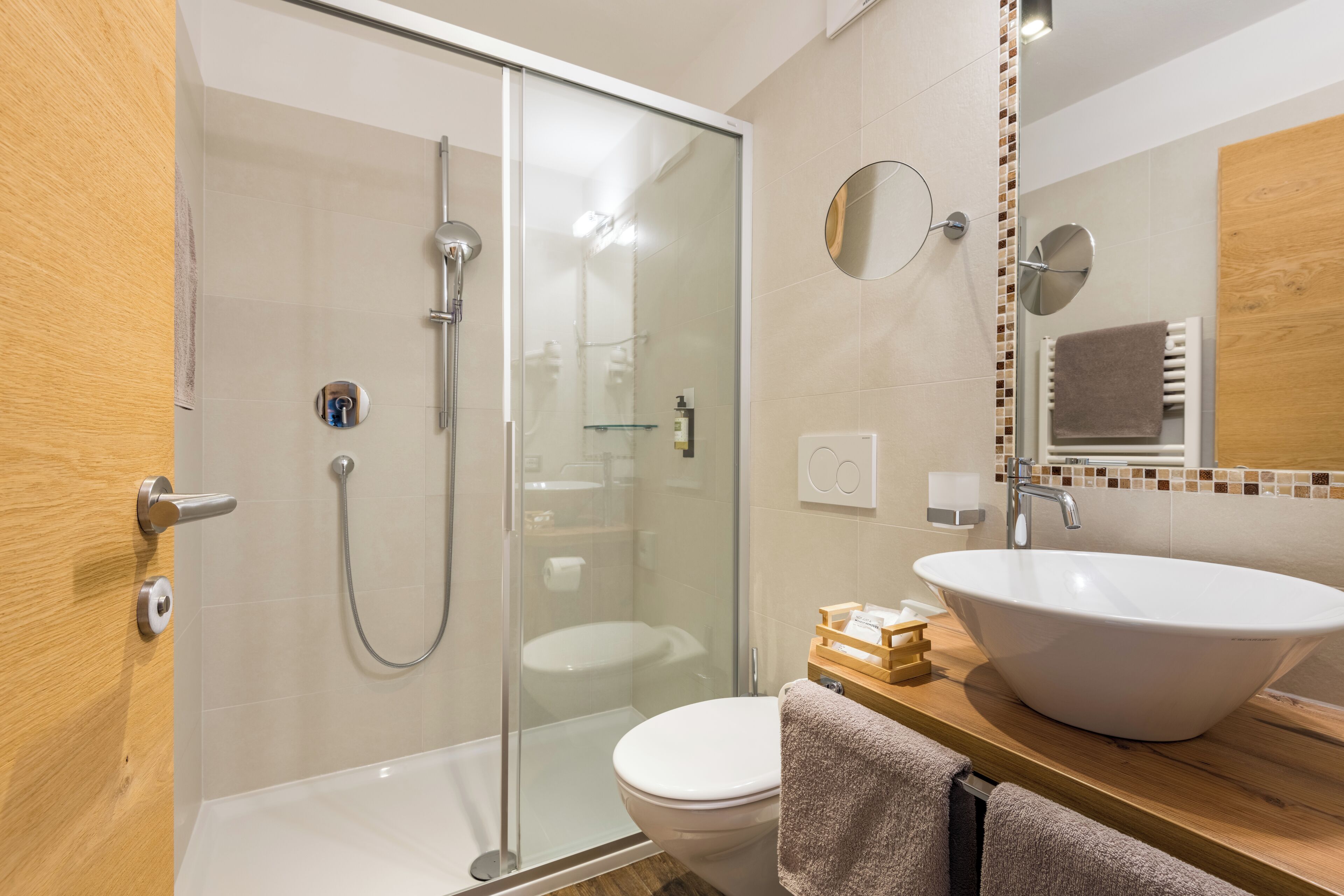 Et moderne badeværelse med et glasvægshus, en hvid vask og et toilet.