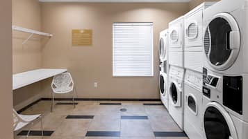 A laundry room with a bench, a chair, and a sign indicating free guest laundry.