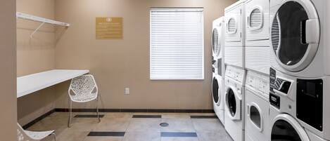 A laundry room with a bench, a chair, and a sign indicating free guest laundry.