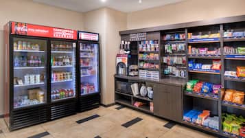 Zona de venta automática con varios refrigeradores y estantes llenos de refrigerios y bebidas.