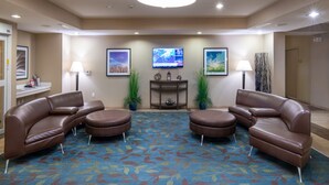 A hotel lobby with a large flat-screen TV, two sofas, a coffee table, and a patterned carpet. - Candlewood Suites Enid by IHG (Enid)