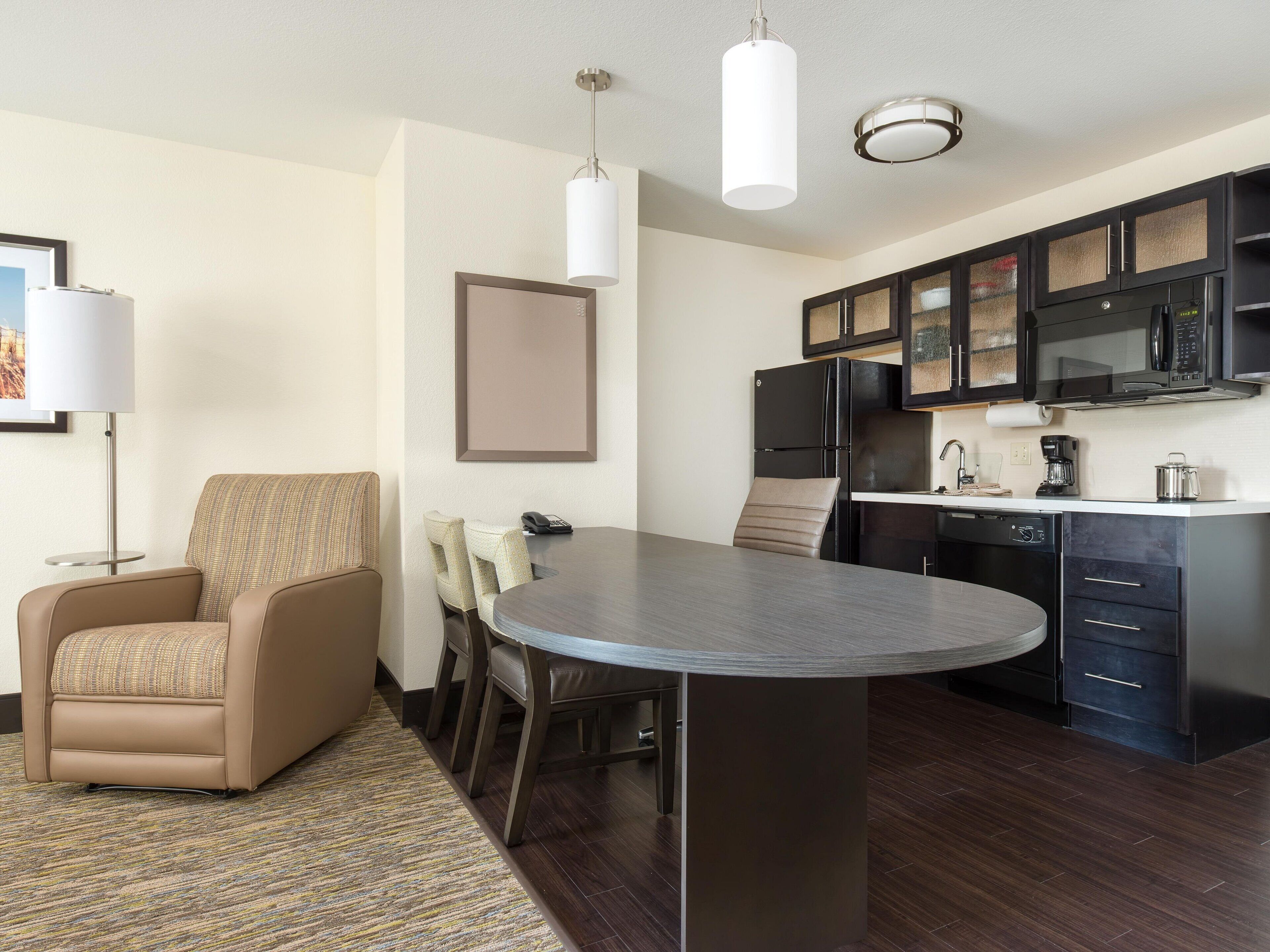 Una cocina moderna con una isla central, suelo de madera oscura y un comedor con sofá y sillas.