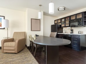 Una cocina moderna con una isla central, suelo de madera oscura y un comedor con sofá y sillas.