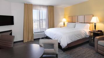 A hotel room with a bed, two bedside lamps, a flat-screen TV, a desk, and a chair.