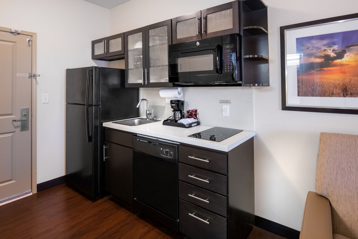 Una cocina compacta equipada con refrigerador, microondas, cafetera y lavavajillas.