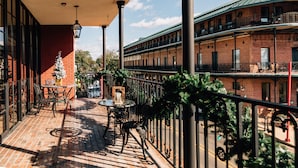 A covered outdoor patio with brick flooring, metal railings, and outdoor furniture. - Church Street Inn (Natchitoches)