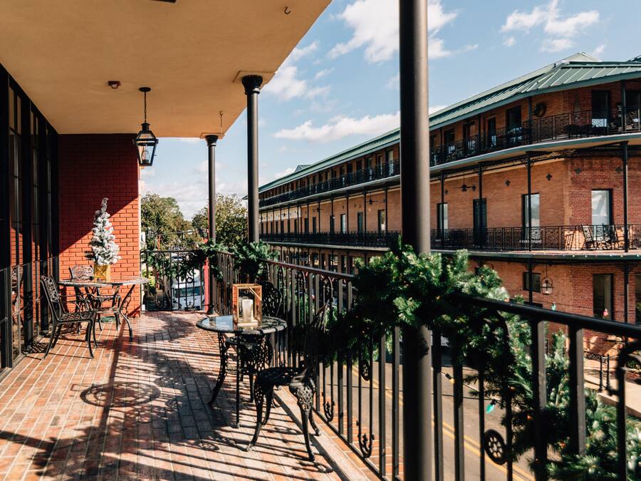 A covered outdoor patio with brick flooring, metal railings, and outdoor furniture.