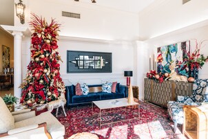 A spacious living room with a large Christmas tree, a blue sofa, and a patterned rug.
