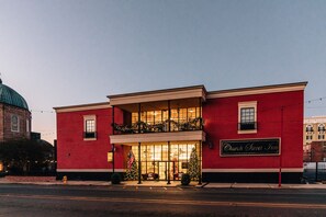 A red brick building with a sign reading "Church Street Inn." It features a balcony with railings and a large windowed entrance.