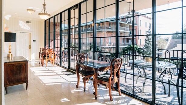A spacious room with a large window, a dining table with chairs, and a small balcony with a table and chairs. - Church Street Inn (Natchitoches)