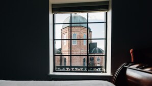 A room with a large window overlooking a historic building with a dome. - Church Street Inn (Natchitoches)