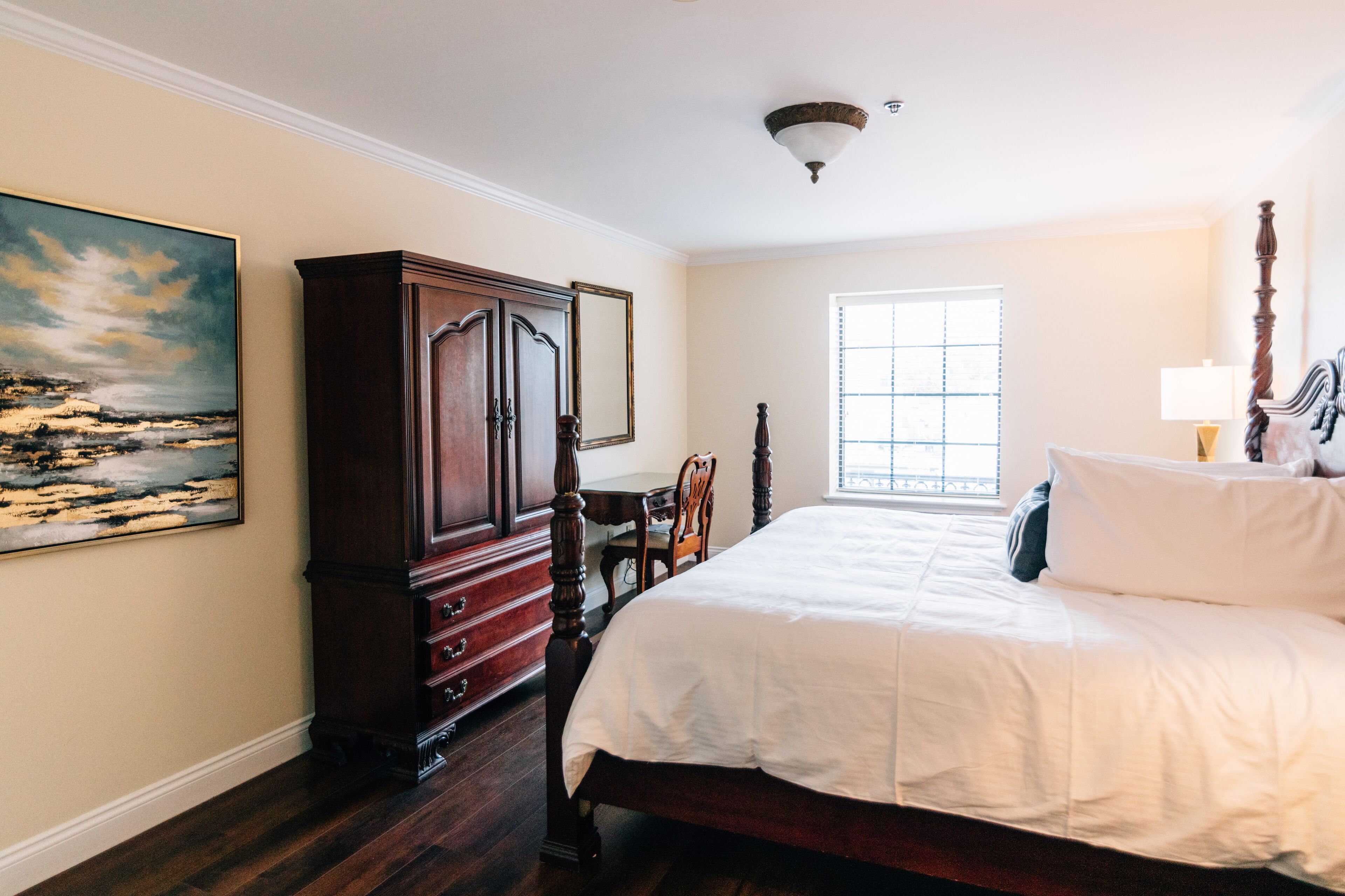 Un dormitorio con una cama grande, un armario de madera, un escritorio y una ventana con persianas.