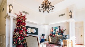 A spacious lobby with a grand chandelier, a large Christmas tree, and a vibrant abstract painting on the wall. - Church Street Inn (Natchitoches)