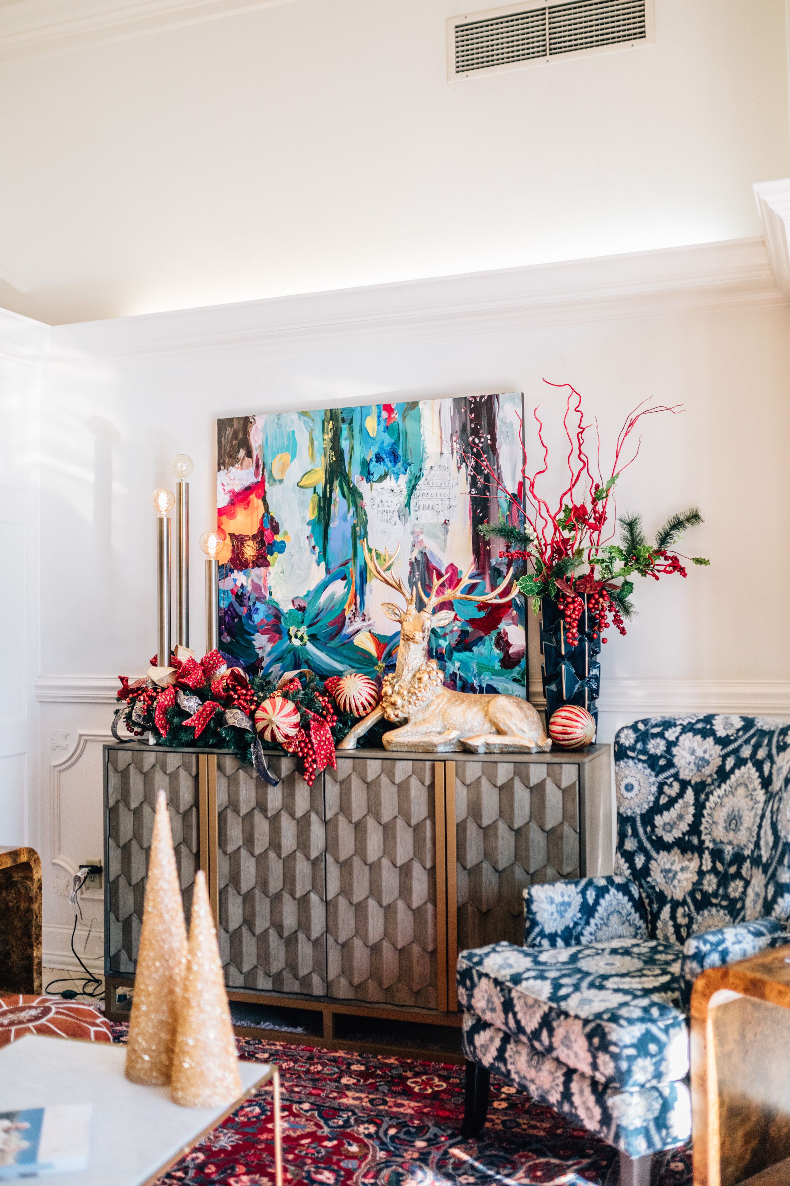 A room with a patterned wall, a decorative table with a painting, and a patterned sofa.