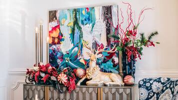 A room with a patterned wall, a decorative table with a painting, and a patterned sofa.