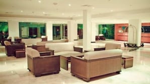 A spacious lobby with multiple seating areas, a reception desk, and a cart. - Kristoff (Maracaibo)