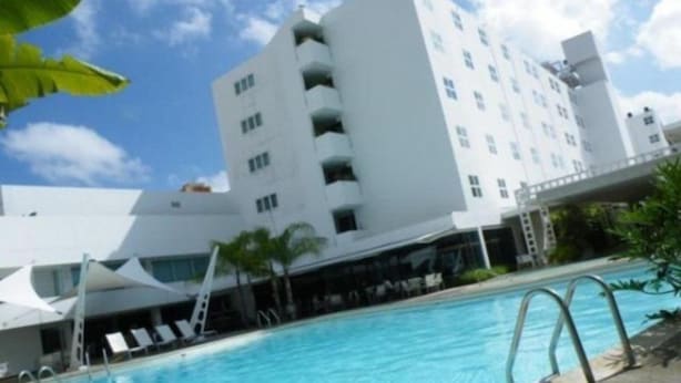 A modern building with a swimming pool, a covered area with lounge chairs, and a clear sky. - Kristoff (Maracaibo)