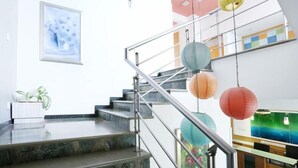 A modern staircase with metal railings, a marble floor, and colorful paper lanterns. - Edha Suites (Bengaluru)
