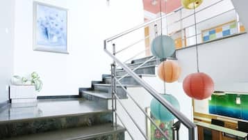 A modern staircase with metal railings, a marble floor, and colorful paper lanterns.
