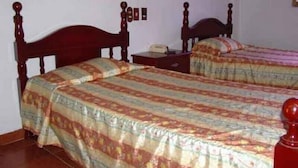 Ein Schlafzimmer mit zwei Holzbetten, einem Nachttisch und einer Wandlampe.