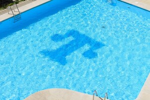 Una piscina al aire libre de temporada, sillones reclinables de piscina