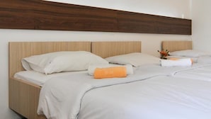 A double bed with a wooden headboard, white bedding, and an orange accent pillow. - Kamelija (Tivat)