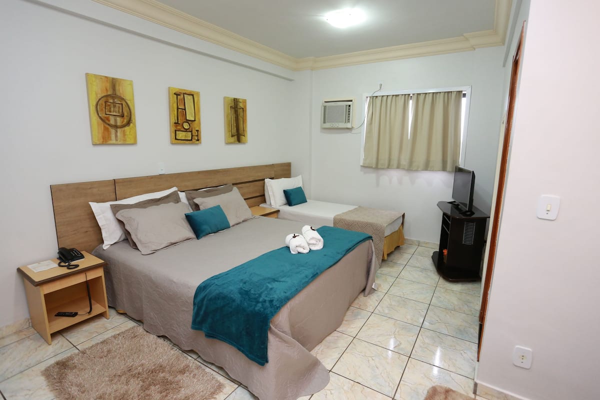 Un dormitorio con una cama grande, una mesita de noche, un televisor y un calefactor.