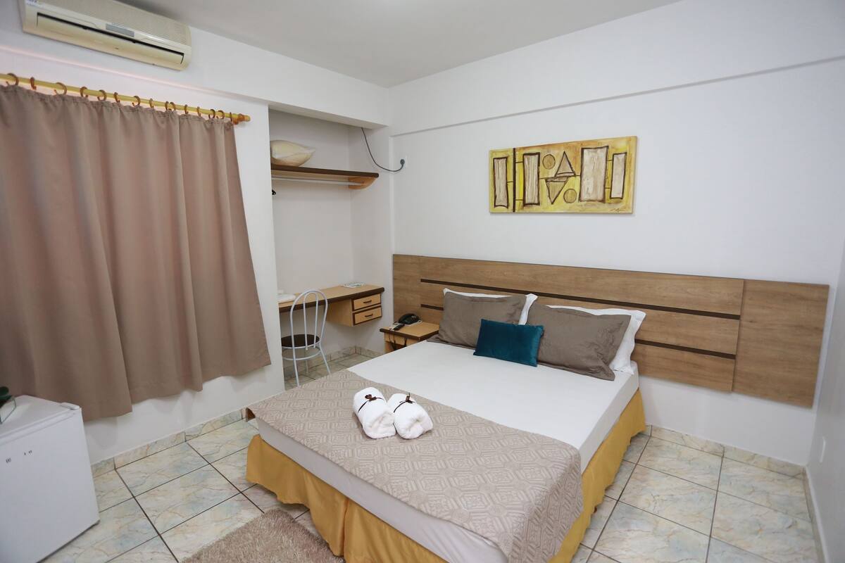 Un dormitorio ordenado con cama, mesita de noche y escritorio.