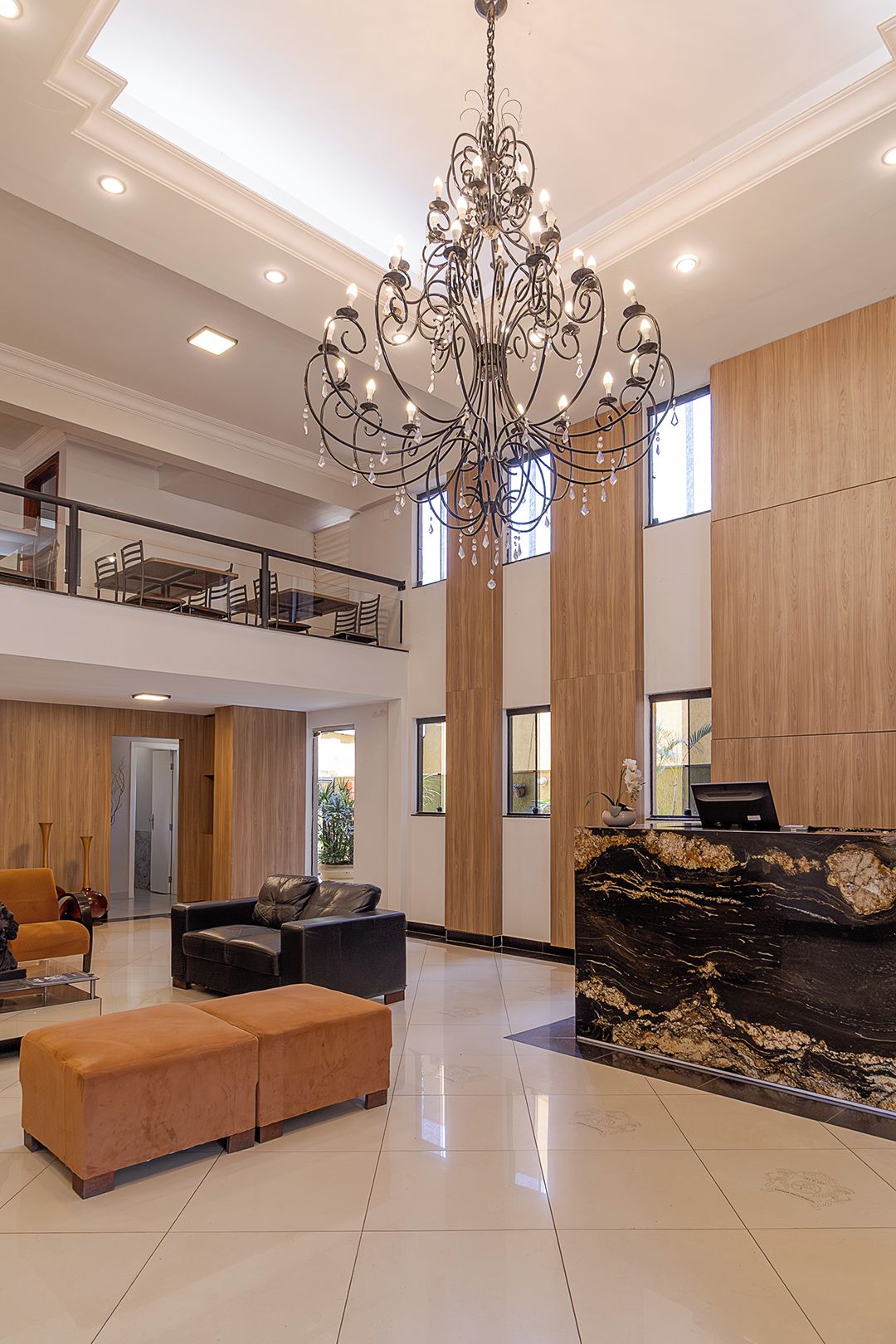 Un vestíbulo amplio con candelabro, zona de estar y mostrador de recepción.