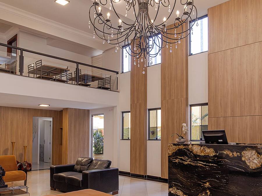 Un vestíbulo amplio con candelabro, zona de estar y mostrador de recepción.