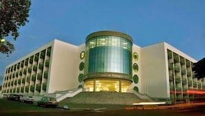 Un bâtiment moderne doté d’une façade en verre incurvée, d’une entrée centrale et d’un escalier menant à l’entrée.
